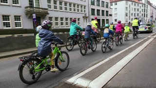 Es sind mehrere Kinder und ein paar Erwachsene auf Fahrrädern zu sehen.