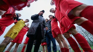 U17-Fußballer vom Blumenthaler SV umringen den Trainer, der einen Ansprache vor dem Spiel hält.