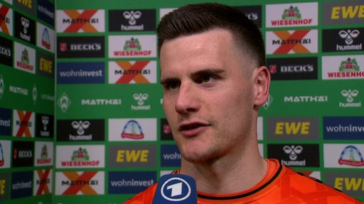Werder-Torwart Michael Zetterer steht nach dem Spiel vor einer Werbewand beim Interview.